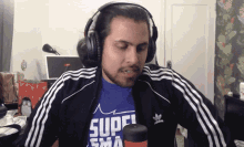 a man wearing headphones and a blue shirt that says super
