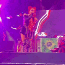 a woman with red hair is standing on a stage with a green box in front of her