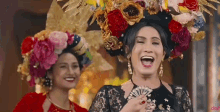 a man dressed as a woman is holding a fan and laughing next to a woman dressed as a woman .