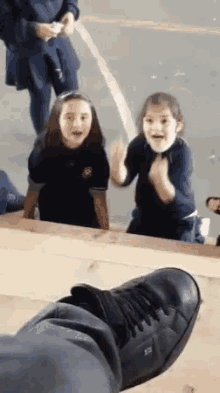 a person 's foot is visible in the foreground of a group of young girls dancing .