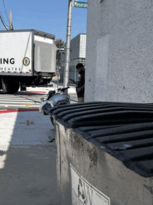 a man looking at his phone in front of a truck that says ing heatre