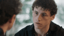a young man with curly hair has a tattoo on his forehead that says ' i love you '