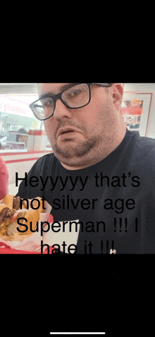 a man wearing glasses and a black shirt is eating a hot dog in a styrofoam container .