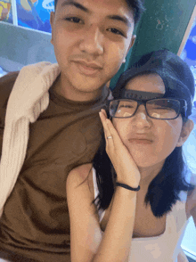 a boy and a girl are posing for a picture and the girl has glasses