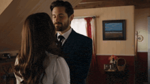 a man in a suit and tie kisses a woman in a living room