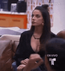 a woman in a black top is sitting on a couch talking to another woman .
