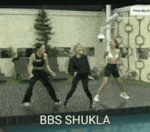 three women are dancing in front of a pool and the words bbs shukla are on the bottom