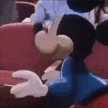 a close up of mickey mouse sitting on a red chair .