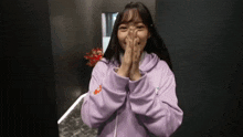 a young woman in a purple hoodie is making a funny face .