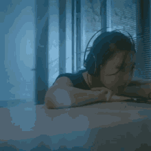 a woman wearing headphones is laying on a desk