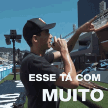 a man talking into a microphone with the words " esse ta com muito " written below him