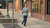 a man in a blue shirt is running down a sidewalk