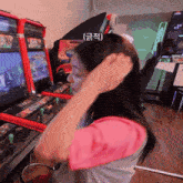 a woman adjusts her hair in front of an arcade machine that says midway on it