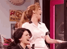 two women laughing in front of a sign that says pretzels