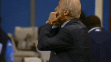 a man in a suit has his hand to his face