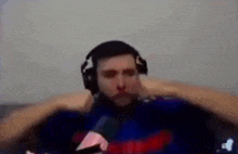 a man wearing headphones is sitting on a couch and covering his ears .