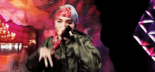 a man wearing a bandana and a beanie is singing into a microphone .