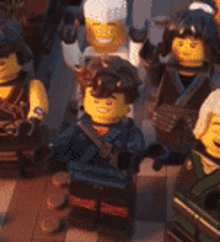 a group of lego figures standing next to each other on a tiled floor .