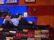 a man in a suit and tie is laying on top of a pile of books