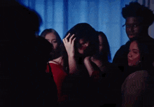 a group of people are standing around a woman