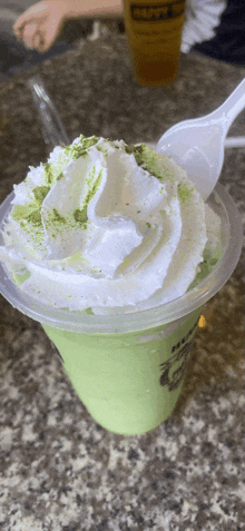 a green drink with whipped cream and matcha sprinkles on top