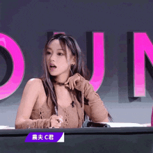 a woman sits at a desk with a sign that says " c " on it
