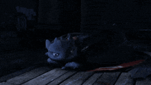 a black dragon laying on a wooden floor with its mouth open