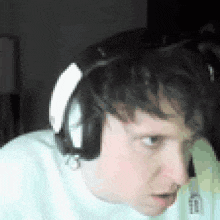 a man wearing headphones and a white shirt is looking at the camera .