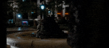 a statue of a frog is sitting in a fountain in the dark