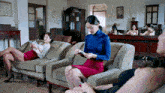 a woman in a blue turtleneck is sitting on a couch