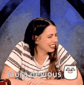 a woman in a striped shirt is sitting at a table with the words laura devious above her