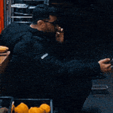 a man wearing glasses and a black jacket is using his phone