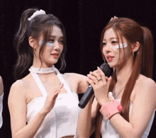 two girls are standing next to each other holding a microphone