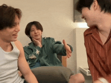 a group of young men are sitting on a couch talking to each other in a living room .