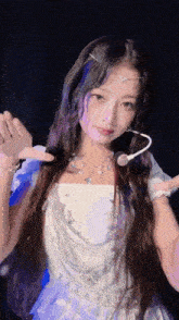 the girl is wearing a white dress and a necklace and has a microphone in her hair .
