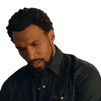 a man with a beard and a denim shirt is looking down