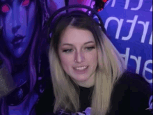 a woman is wearing headphones and smiling in front of a purple background .