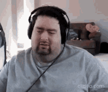 a man with a beard is wearing headphones and looking at the camera .