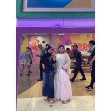 two women standing in front of a sign that says ' pepsi '