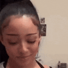 a woman is looking down with her eyes closed and her hair in a bun .