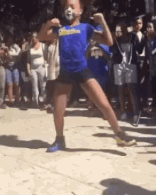 a girl wearing a blue shirt that says ' champions ' on it is dancing in front of a crowd .