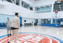 two men are playing basketball on a court with a detroit pistons logo on the floor
