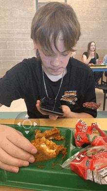 a boy wearing a shirt that says jacksonville jaguars is eating fried chicken