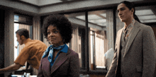 a man in a suit and tie stands next to a woman in a purple suit