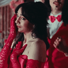 a woman in a red dress and red gloves is standing in front of a man in a red suit .