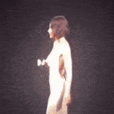 a woman in a white dress is singing into a microphone on stage .