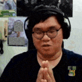 a man wearing glasses and headphones is praying with his hands together