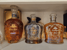 three bottles of crown royal whiskey sit on a shelf