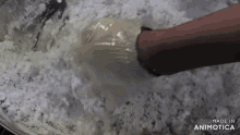 a person wearing a glove is mixing a powdered substance in a bowl .