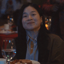 a woman with long black hair is smiling while sitting at a table